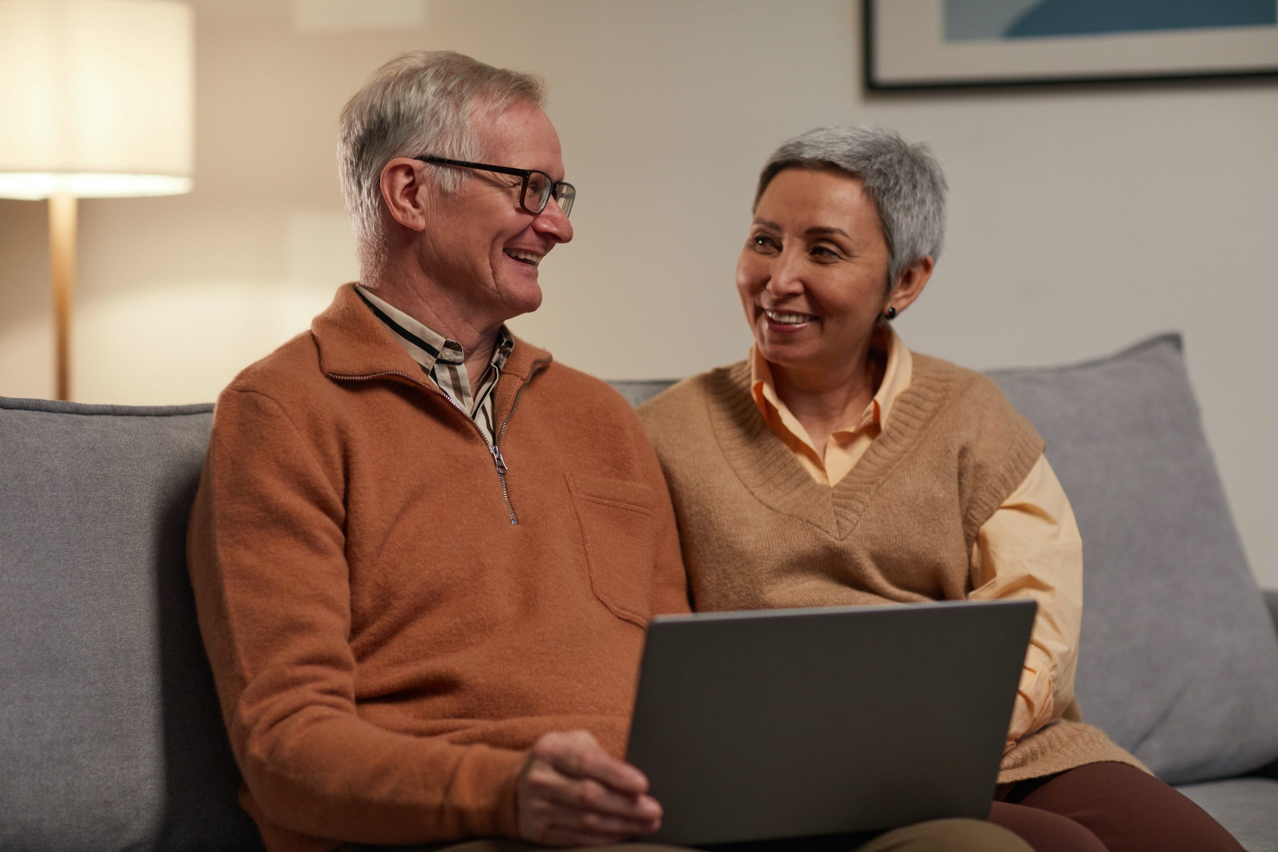 smiling couple looking at laptop on a couch